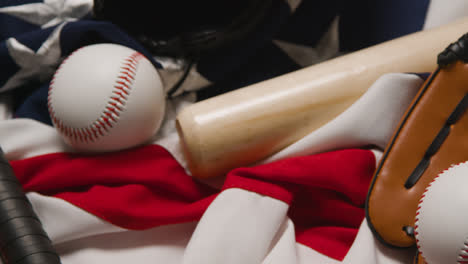 Baseball-Stillleben-über-Dem-Kopf-Mit-Fängerhandschuh-Auf-Amerikanischer-Flagge,-Während-Person-Schläger-Und-Ball-Aufhebt